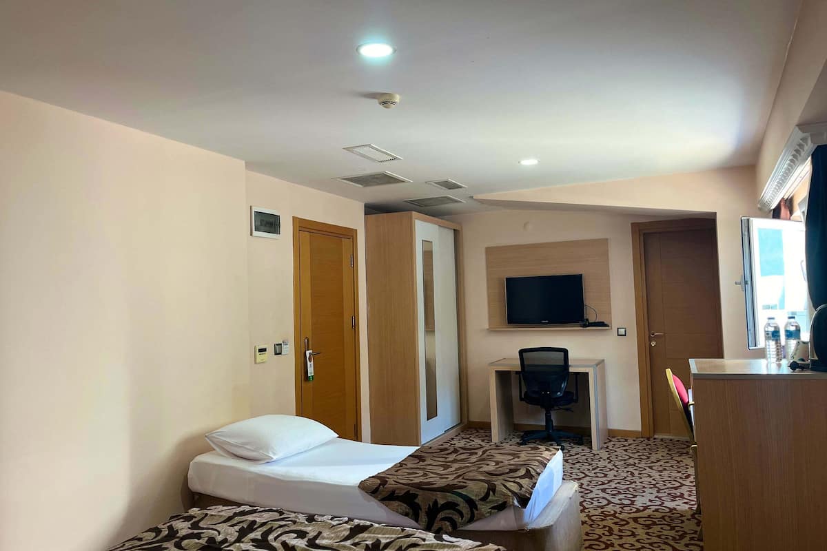 A hotel room with two beds, a desk, a chair, a television, and a minibar.