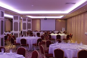 A banquet hall with multiple round tables set for dining, equipped with white tablecloths and red chairs. - Ottoman Hotel Sakarya (Adapazari)