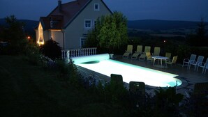 Una casa con piscina, mobiliario exterior y vistas al campo.