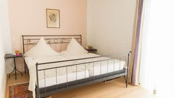 A neatly made bed with a metal frame, a bedside table with a lamp, and a framed picture on the wall.