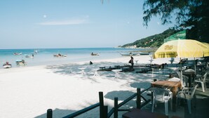 A beachside restaurant with outdoor seating, a view of the sea, and several boats in the water. - Haadrin Resort (Ko Pha-ngan)