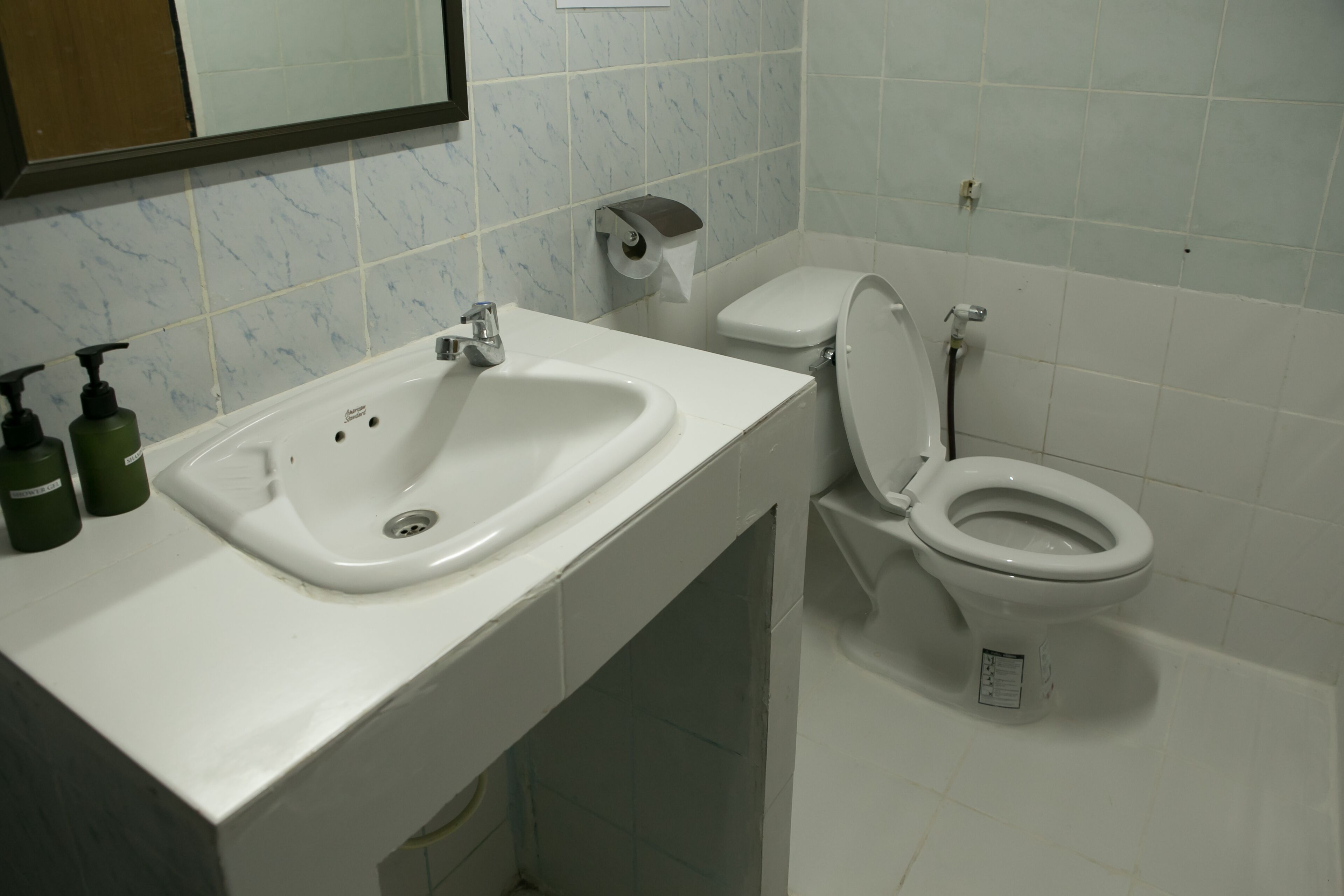 A bathroom with a sink, toilet, and hand soap dispensers.