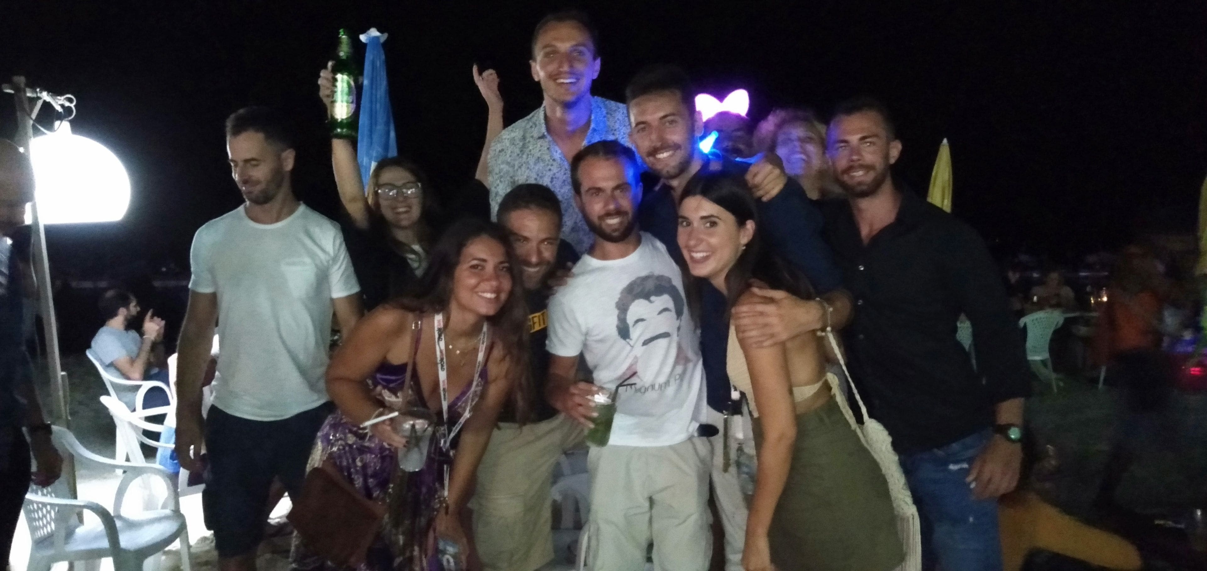 A group of people gathered outdoors at night, possibly at a social event.
