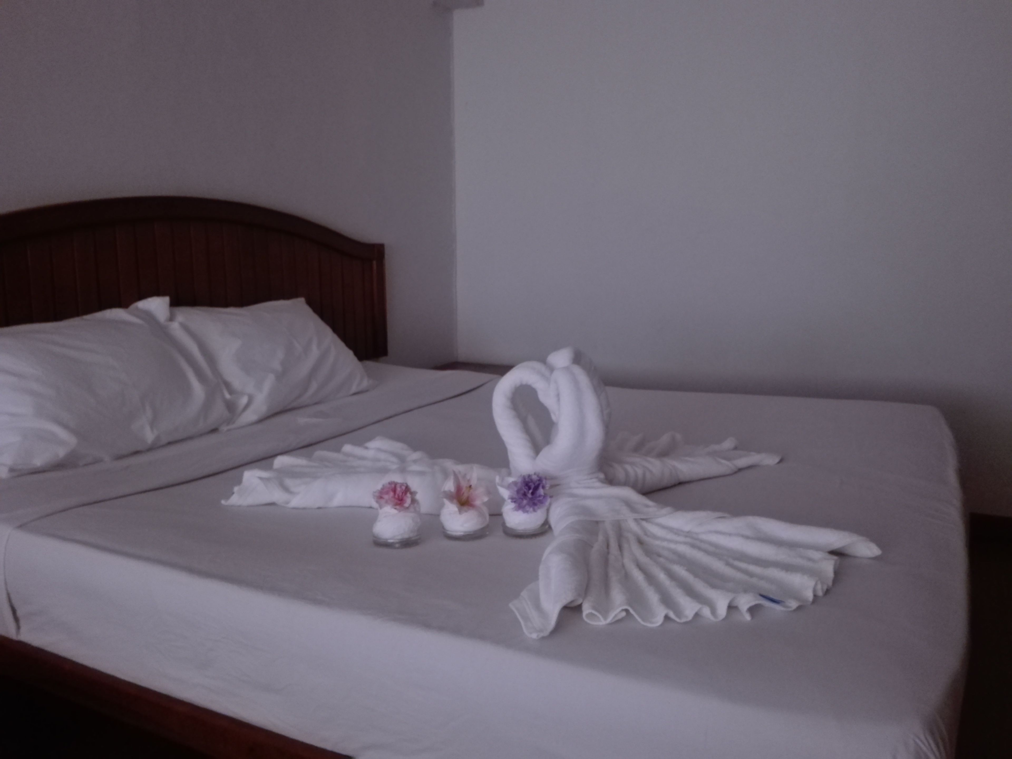 Ein ordentlich bezogenes Bett mit einer Schwanen- und Blumenkomposition.
