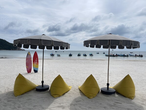 A beach with two umbrellas and yellow bean bags. - Haadrin Resort (Ko Pha-ngan)