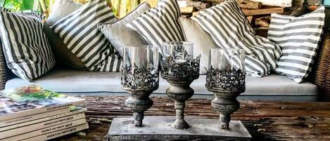 A cozy living area with a stone wall, striped pillows, and decorative glass vases on a wooden table.