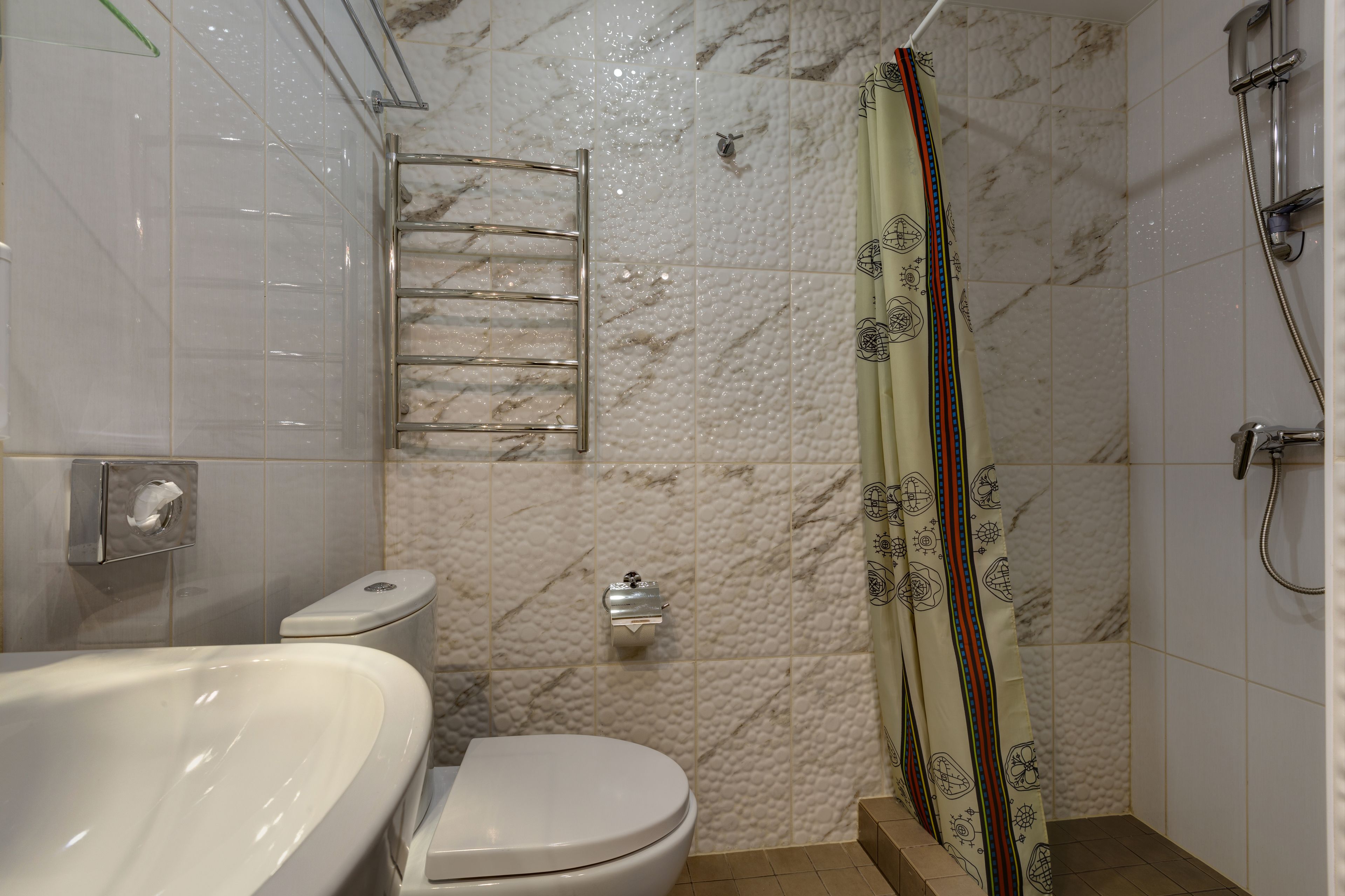 Un baño con bañera, inodoro, ducha y un perchero para toallas.
