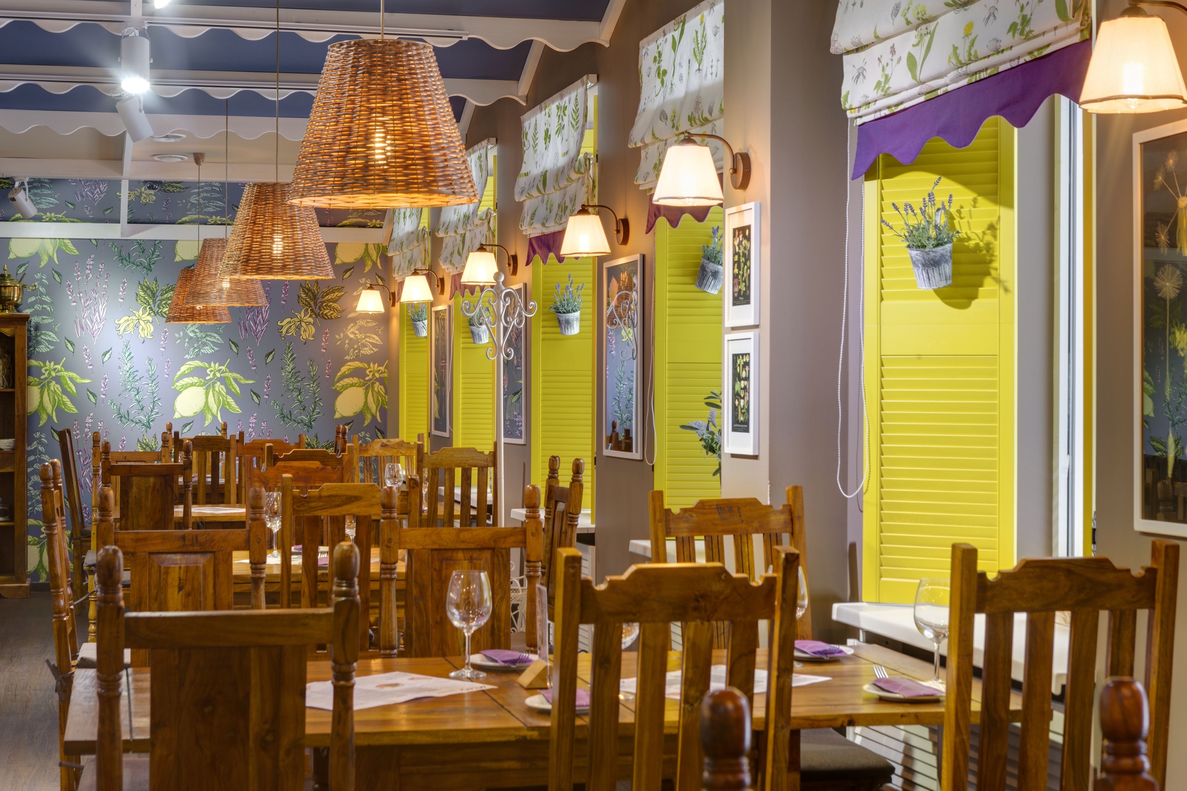 A restaurant with wooden tables and chairs, hanging lamps, and a vibrant mural on the wall.
