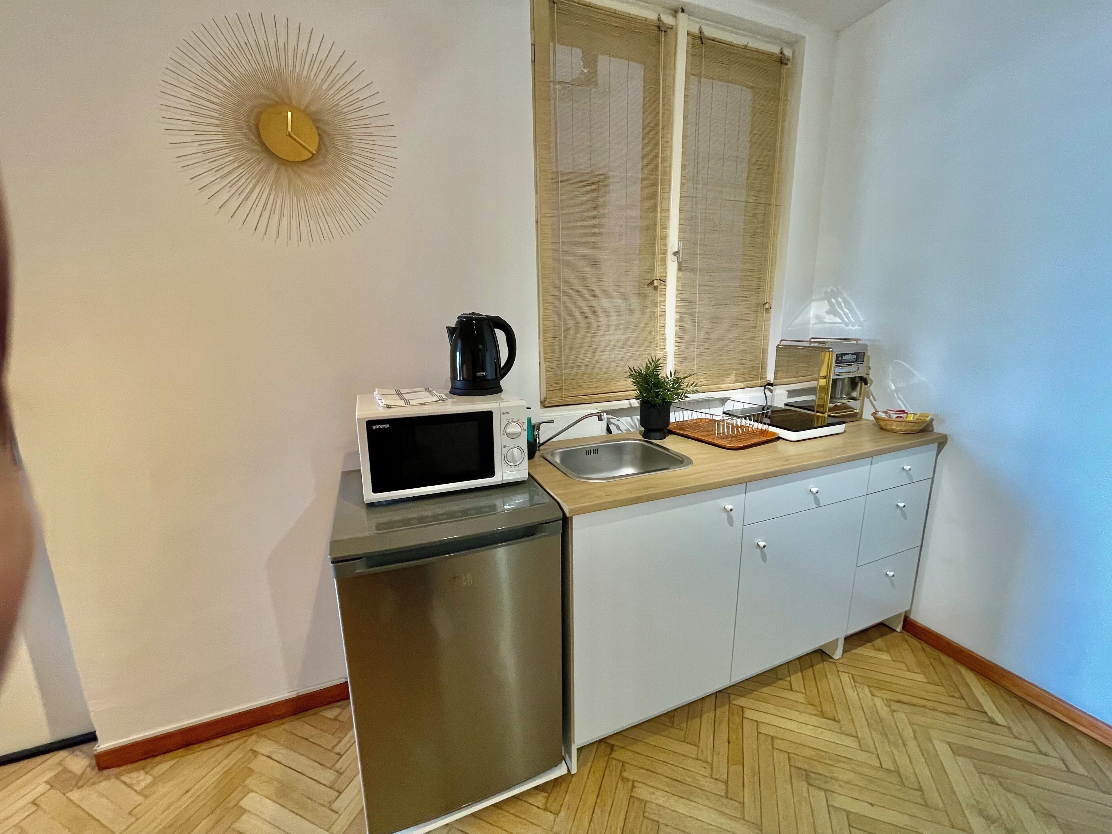 Cocina compacta con microondas, cafetera y lavabo.