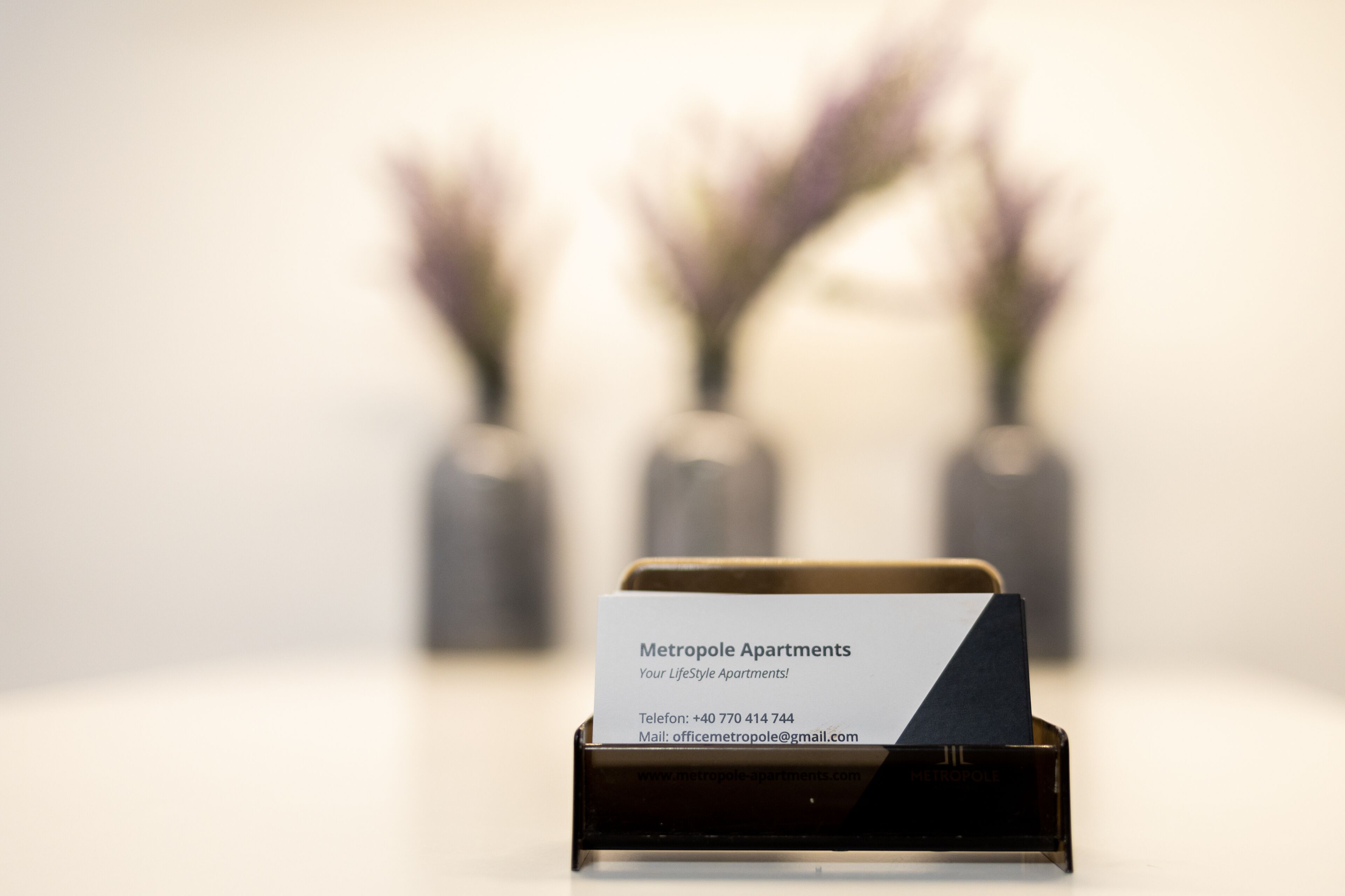 A business card for Metropole Apartments with contact information.
