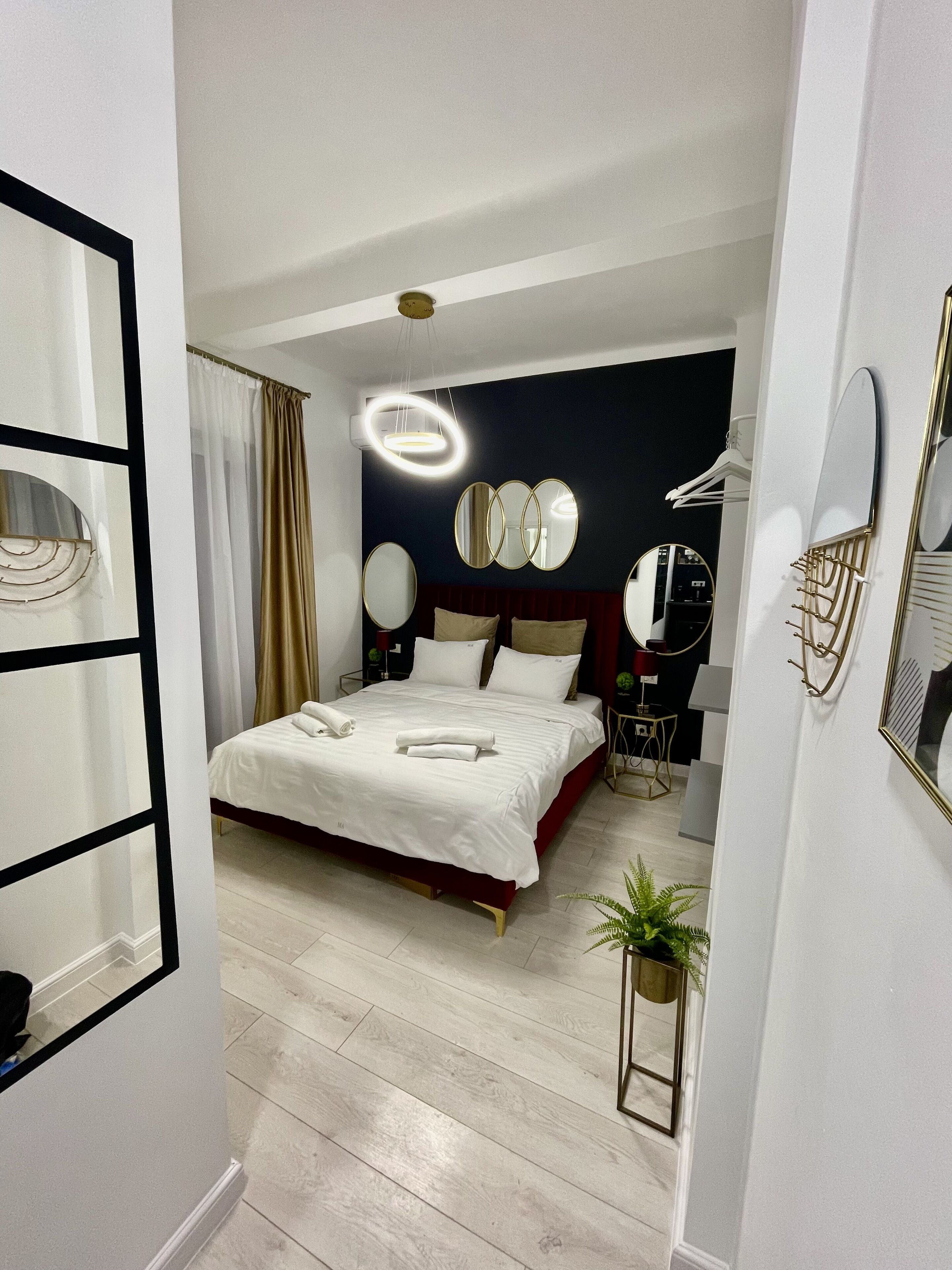Een moderne hotelkamer met een groot bed, nachtkastjes, een bureau en een spiegel.
