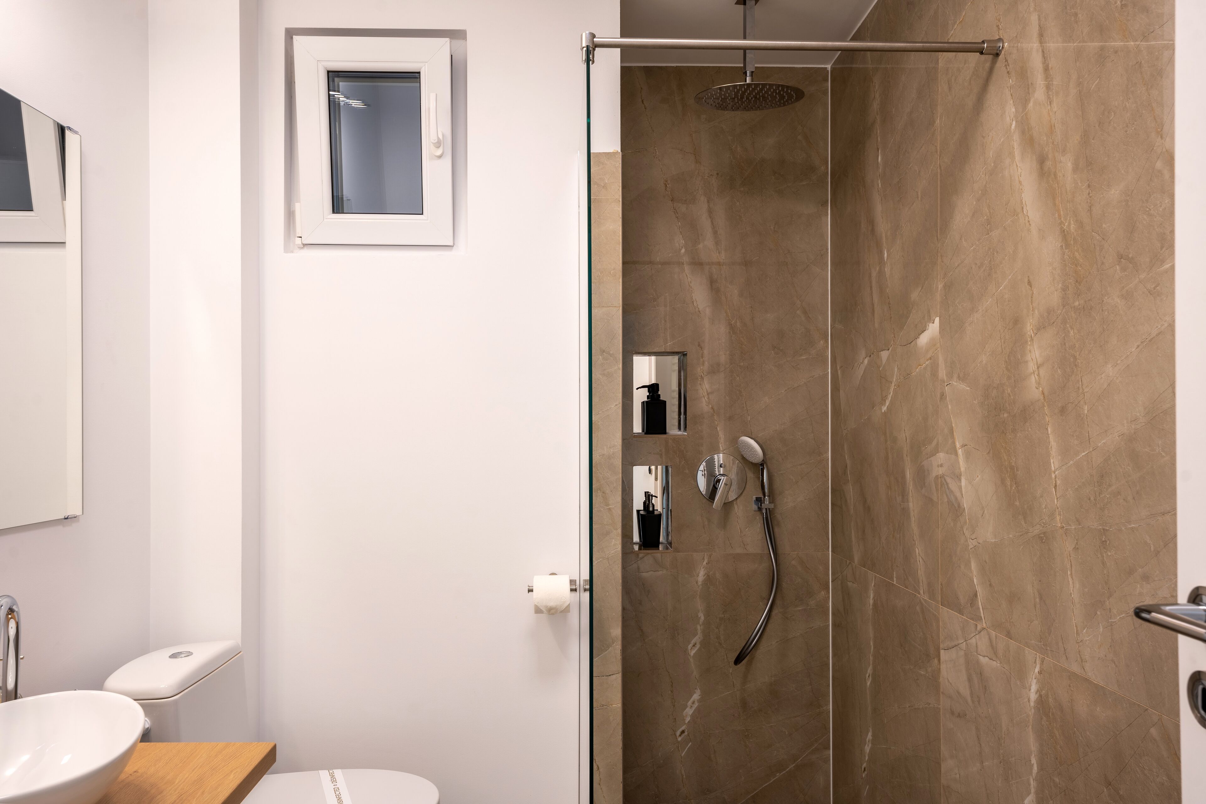 Un baño moderno con ducha de vidrio, inodoro y lavamanos.