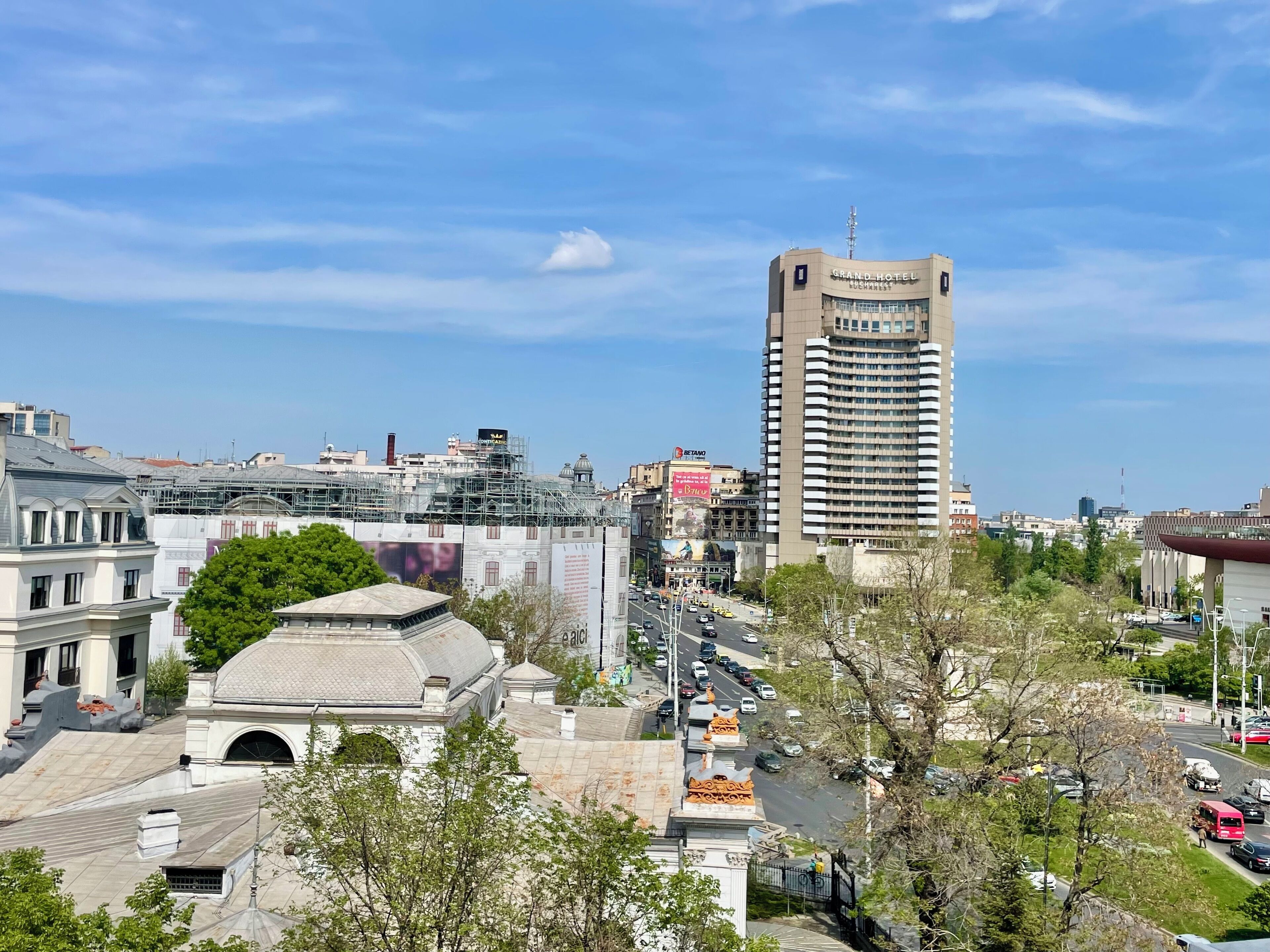 Un paisaje urbano con un imponente edificio del Grand Hotel, rodeado de otros edificios y una calle concurrida.