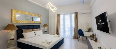 A modern hotel room with a large bed, bedside lamps, a TV, and a desk with a chair.