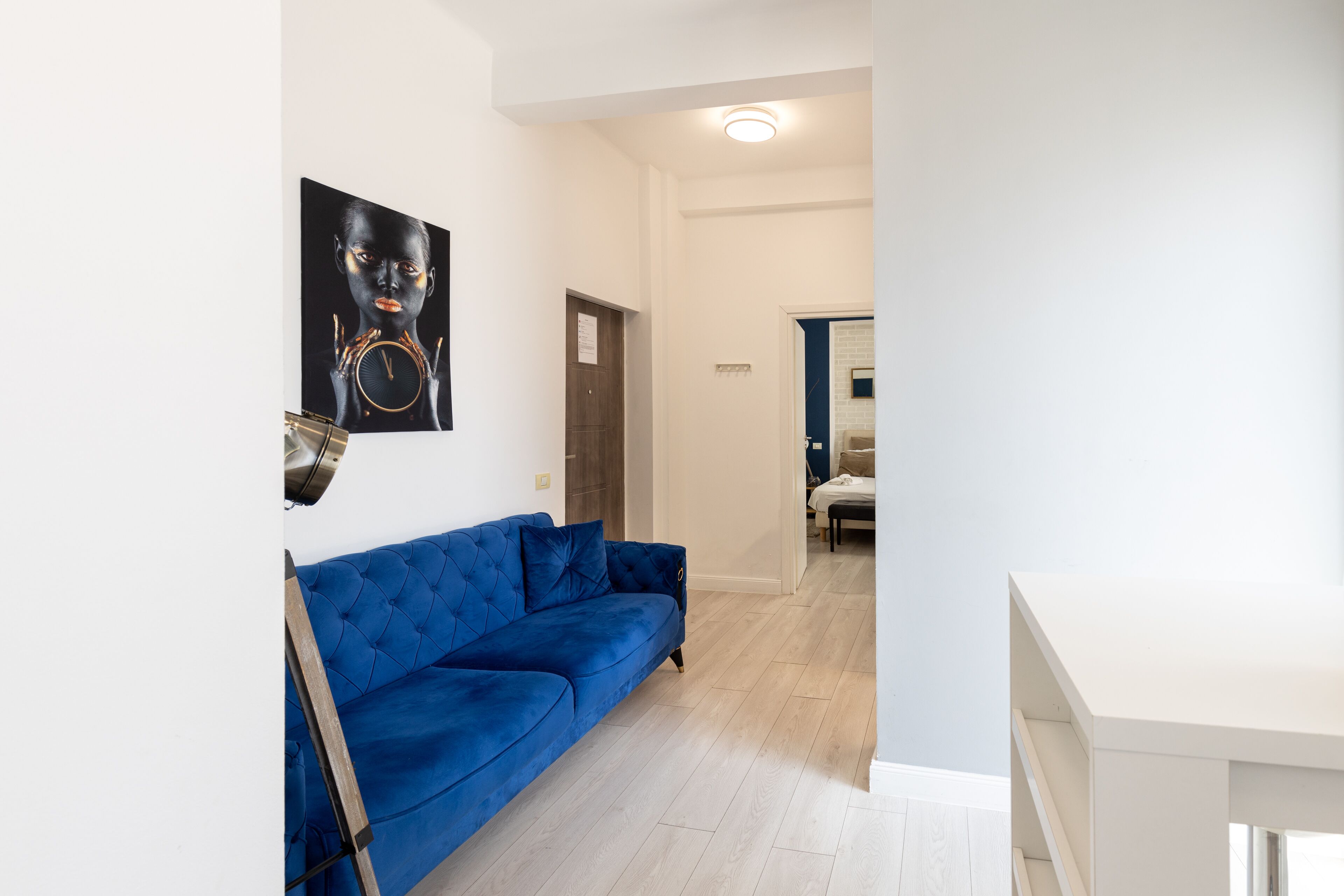 Una sala de estar moderna con un sofá azul, un cuadro en la pared y suelo de madera.