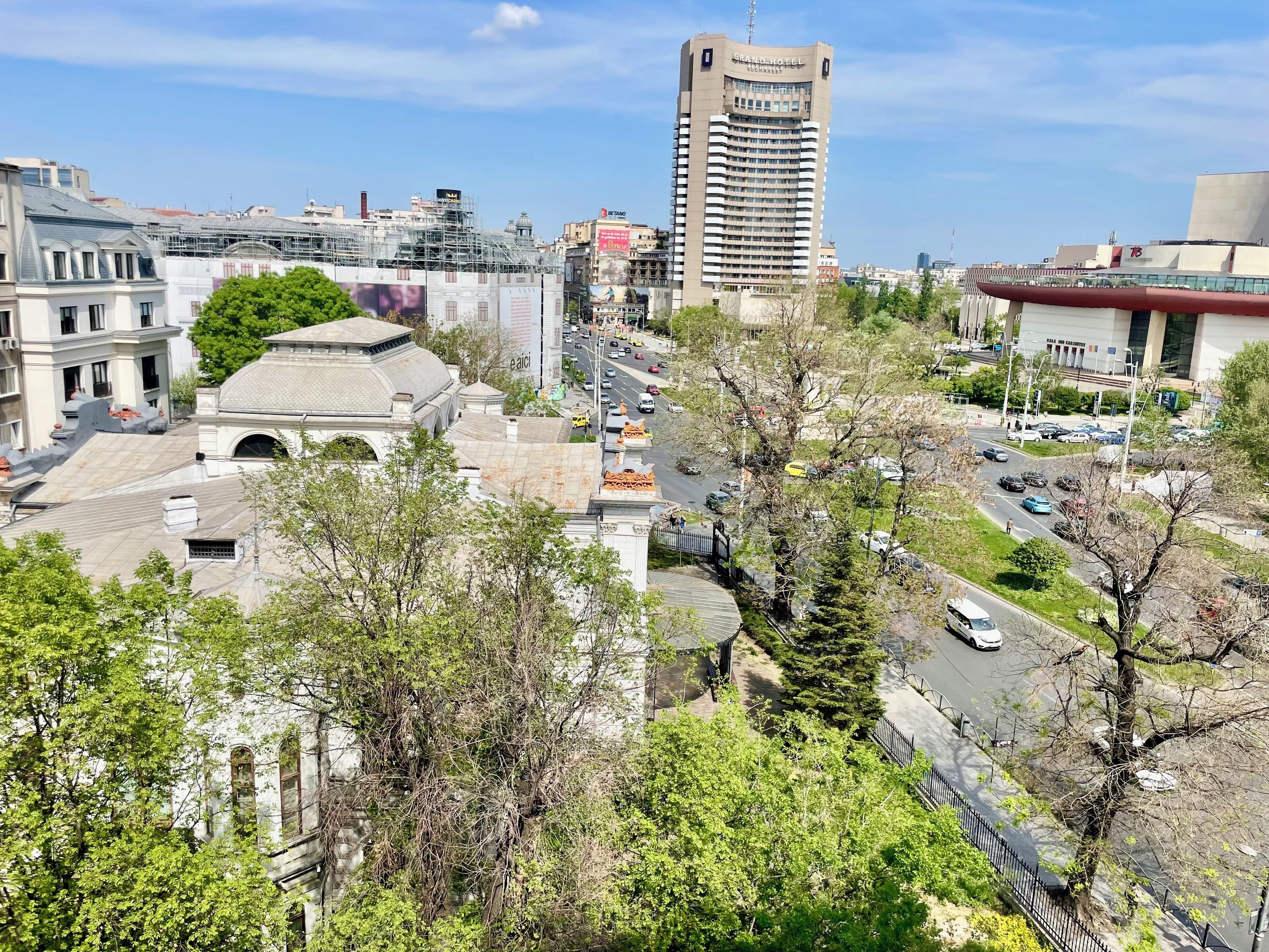 Paisagem urbana com um hotel em destaque, uma rua movimentada e edifícios ao redor.
