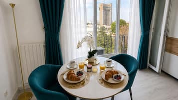 Comedor con una mesa redonda, dos sillas y vistas a un paisaje urbano a través de amplios ventanales.