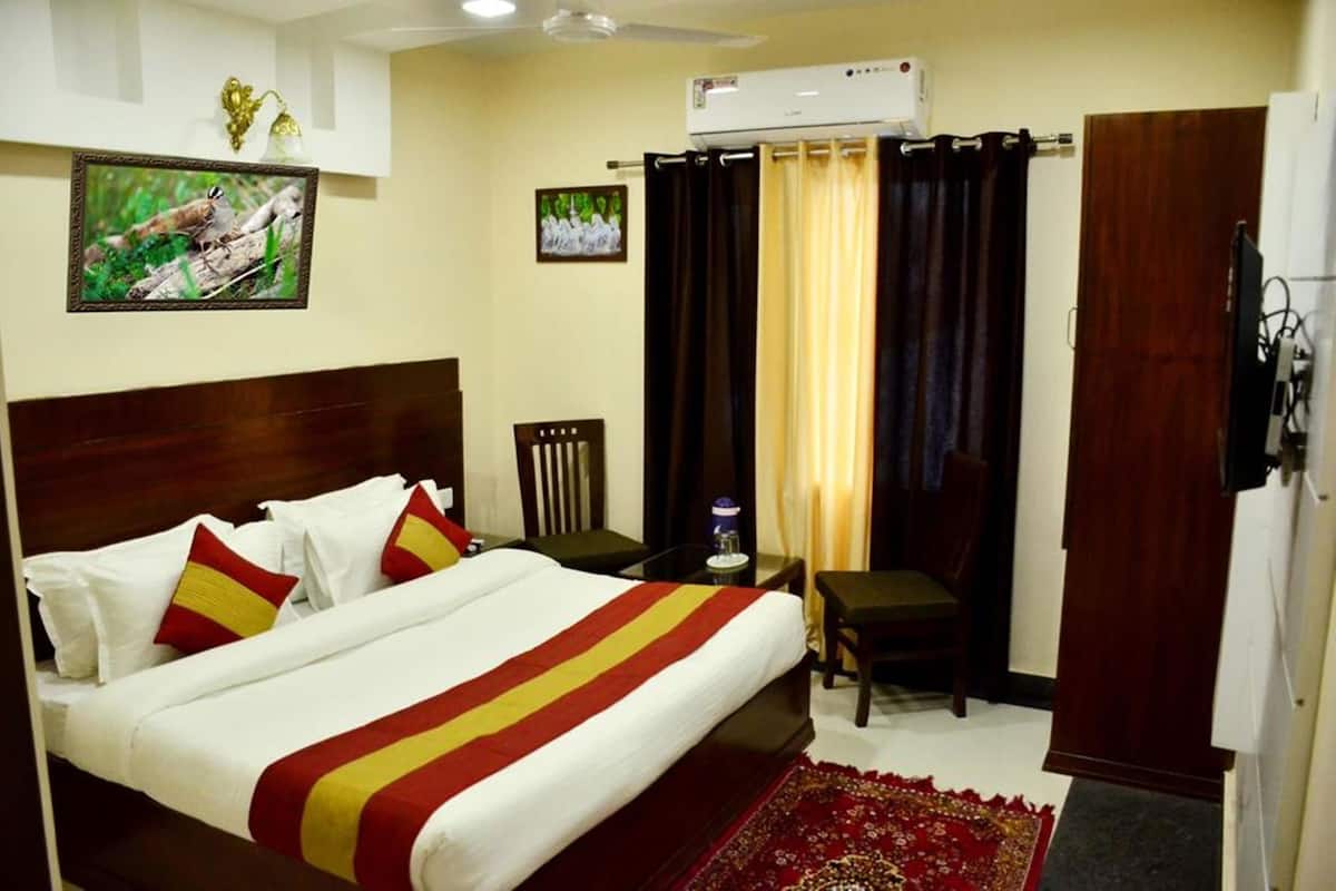 Ein Hotelzimmer mit Bett, Schreibtisch, Sessel, Klimaanlage und Fernseher.