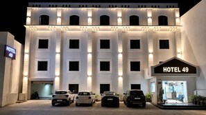A hotel building with multiple floors, a sign indicating 'HOTEL 49', and several parked cars in front. - Hotel 49 (Amritsar)