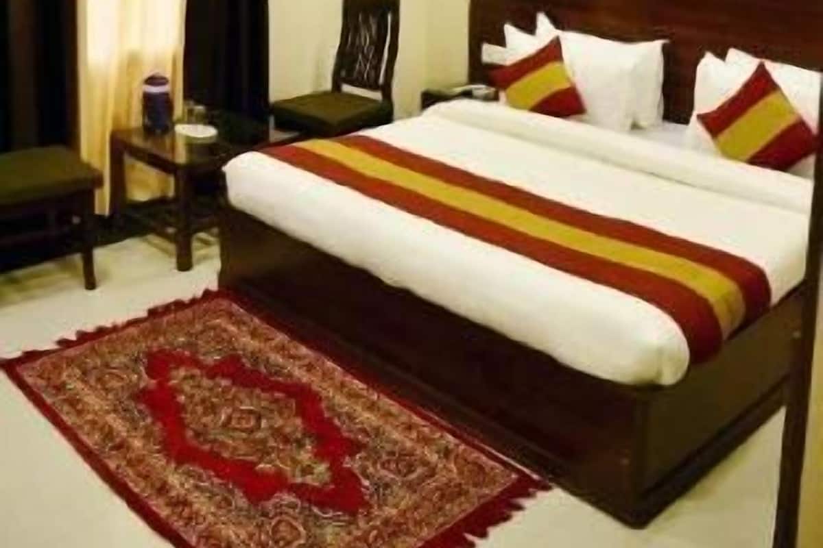 Ein Hotelzimmer mit einem Bett, einem Sessel, einem kleinen Tisch und einem dekorativen Teppich.