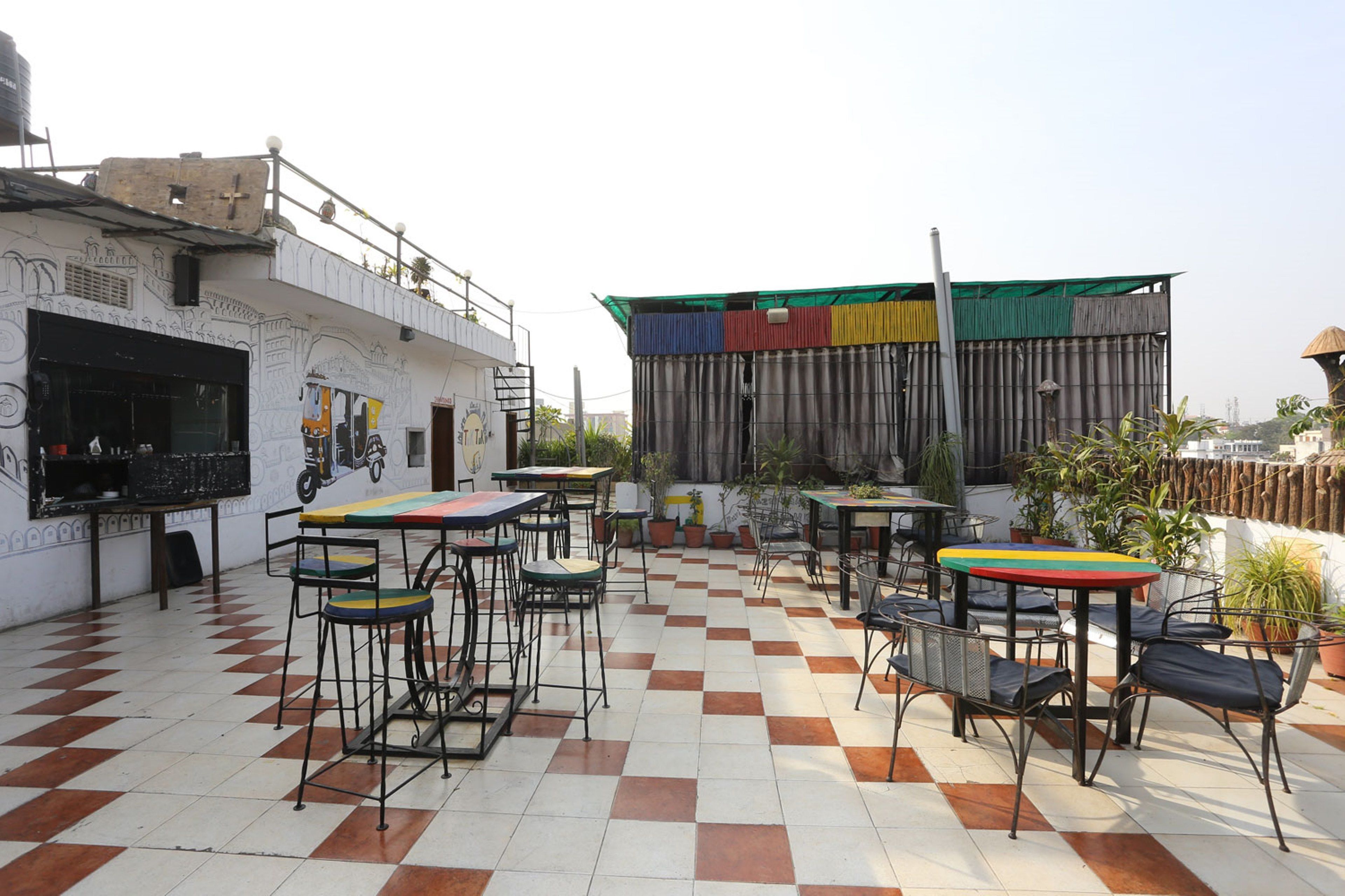 Un café al aire libre con suelo a cuadros, mesas y sillas de metal.