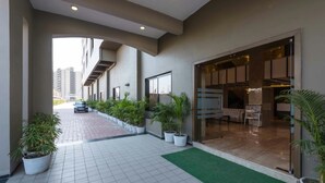 A modern hotel corridor with potted plants, a car parked outside, and a view of the cityscape. - Hotel Park Palace (Ujjain)