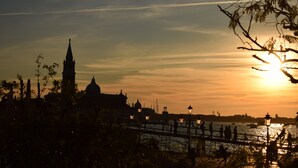Una vista al atardecer de un paisaje urbano con una torre destacada y un puente sobre el agua.