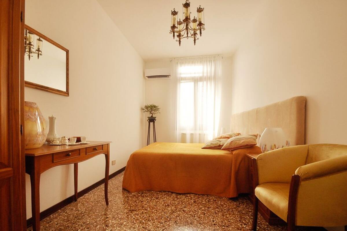 Una habitación de hotel con una cama, una silla, un escritorio y una araña.