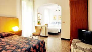 Una habitación de hotel con cama, escritorio, silla, televisor y armario de madera.