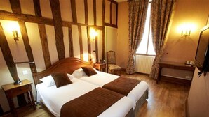 A traditional room with exposed wooden beams, a large bed with two pillows, a bedside table, a chair, and a mirror. - Logis Relais Saint Vincent (Ligny-le-Chatel)