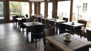 A restaurant with multiple tables and chairs, large windows, and a view of the outdoors. - Logis Relais Saint Vincent (Ligny-le-Chatel)