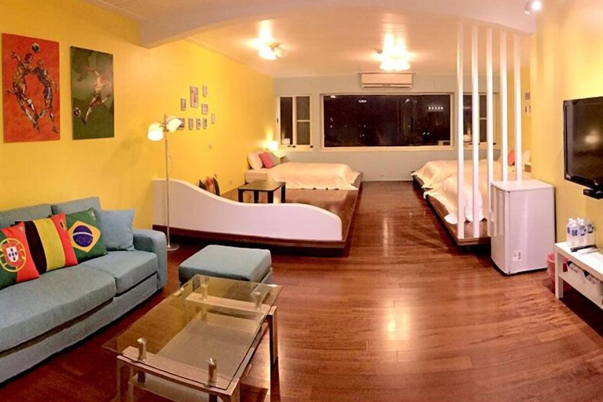 Un espacio habitable compacto con sofá, cama, televisor y refrigerador.