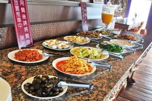 Una mesa de buffet con diversos platos, como pasta, ensaladas y carnes, en un restaurante.