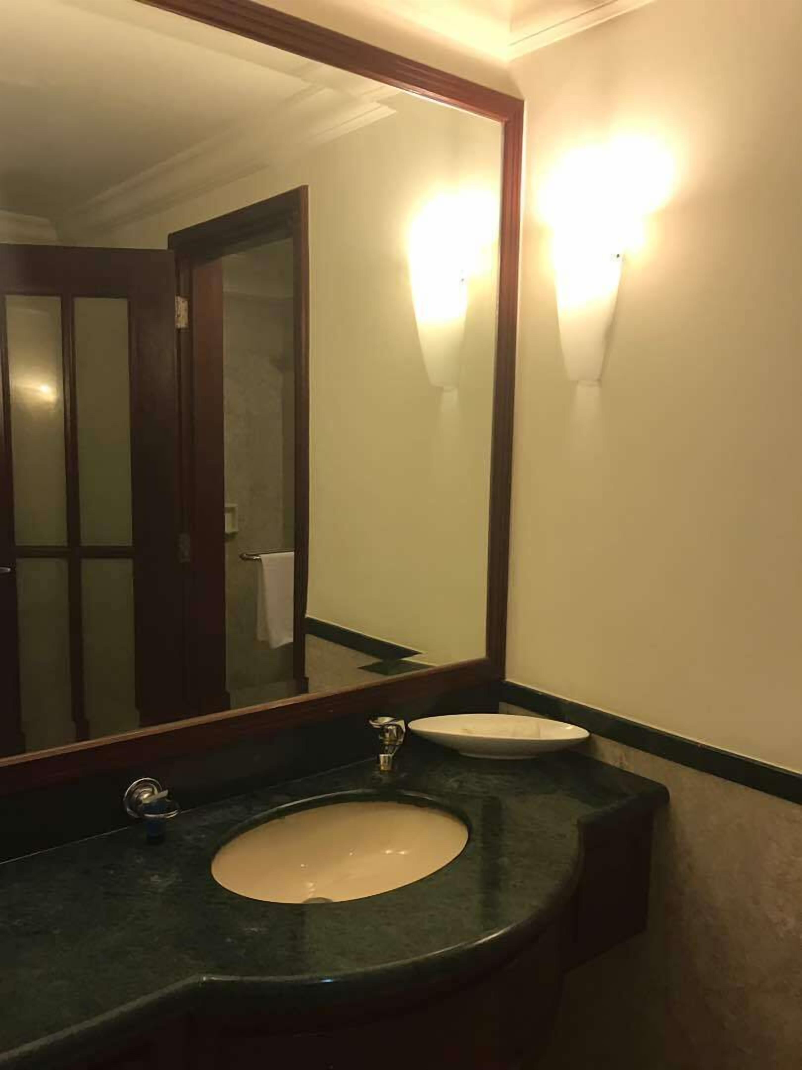 A bathroom with a large mirror, a sink, and two wall-mounted lights.