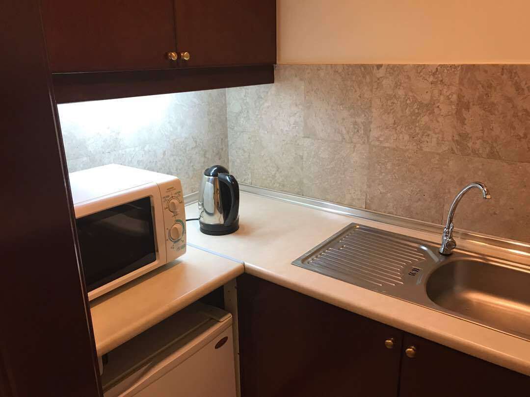 A compact kitchen with a microwave, kettle, and sink.