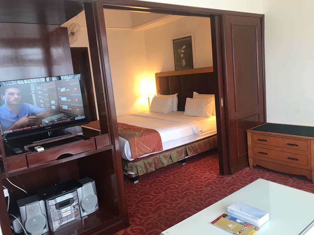 A hotel room with a bed, a TV, a desk, and a dresser.