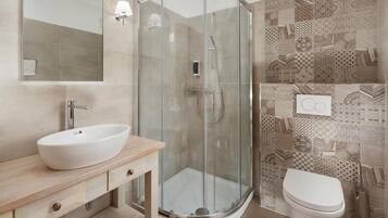 Et moderne badeværelse med et glasafskærmet brusebad, en hvid vask og et toilet.