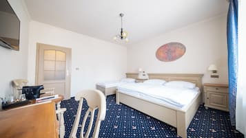 Une chambre d’hôtel avec deux lits, un bureau, une chaise, une lampe de bureau, une table de chevet et une œuvre d’art accrochée au mur.