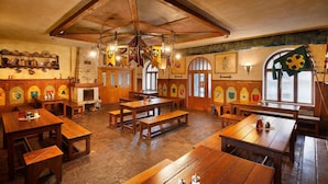 A traditional pub with wooden tables and benches, stone walls, and various flags and banners. - Hotel U Kata (Kutna Hora)