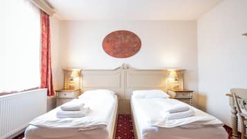 A hotel room with two single beds, a round wall decoration, and a red carpet.