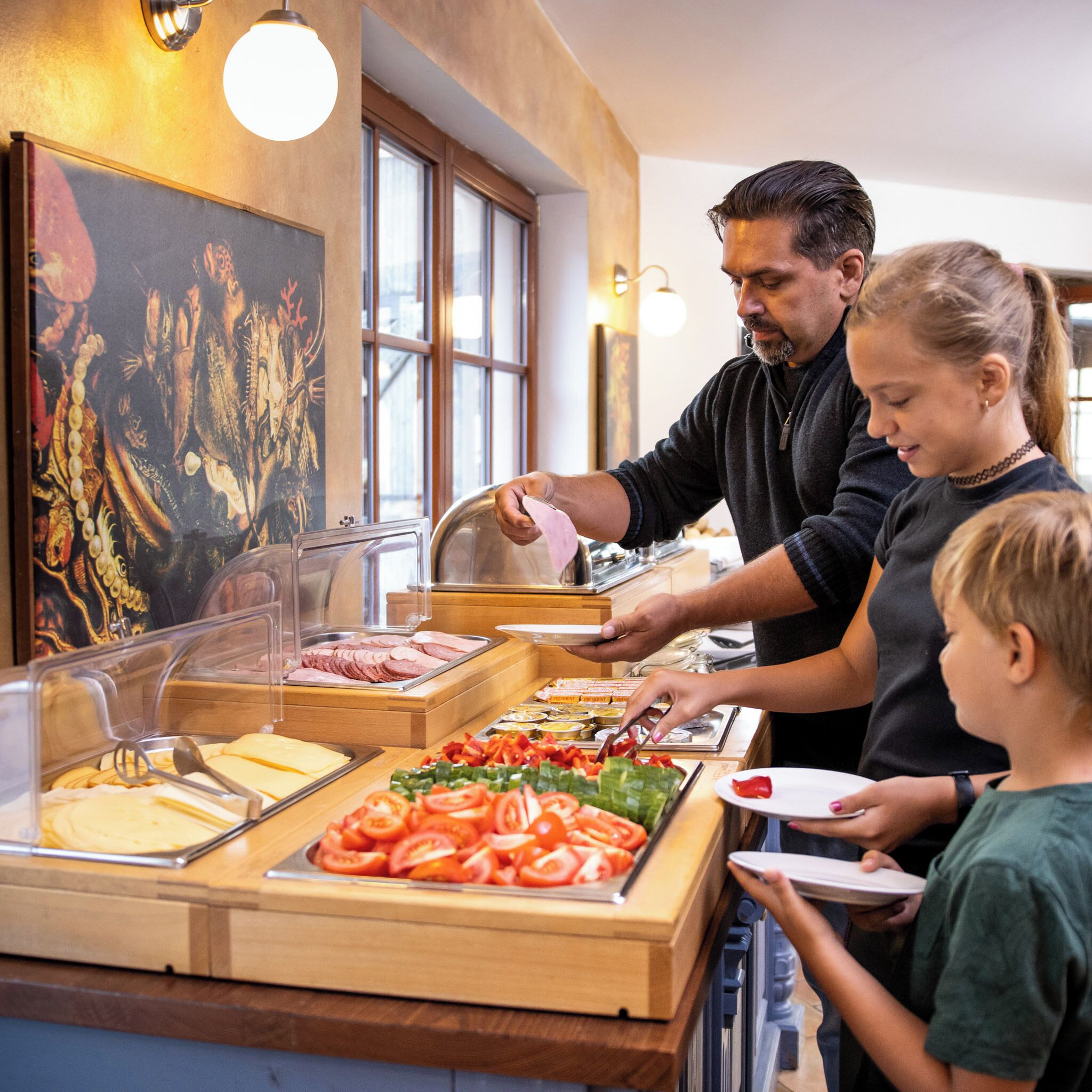 A buffet setup with various food items and a person serving.