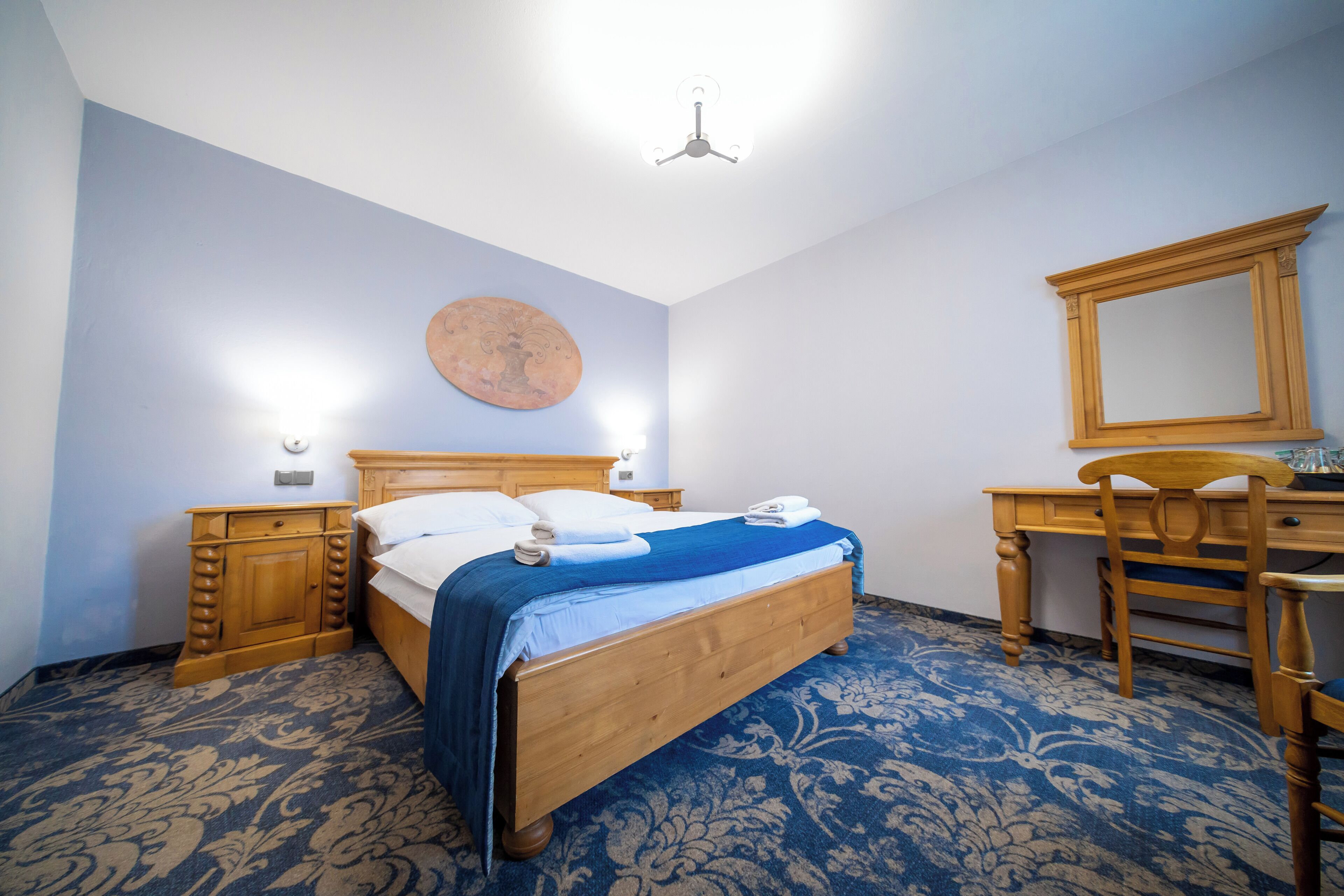 Un dormitorio con una cama de madera, una mesita de noche, un escritorio y una silla.