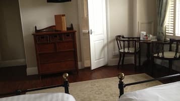 Una habitación de hotel con dos camas, un aparador, un televisor y un rincón de comedor con sillas y una mesa.