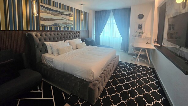 Ein modernes Hotelzimmer mit einem großen Bett, einem Schreibtisch und einem Fernseher.