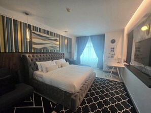 Ein modernes Hotelzimmer mit einem großen Bett, einem Schreibtisch und einem Fernseher.