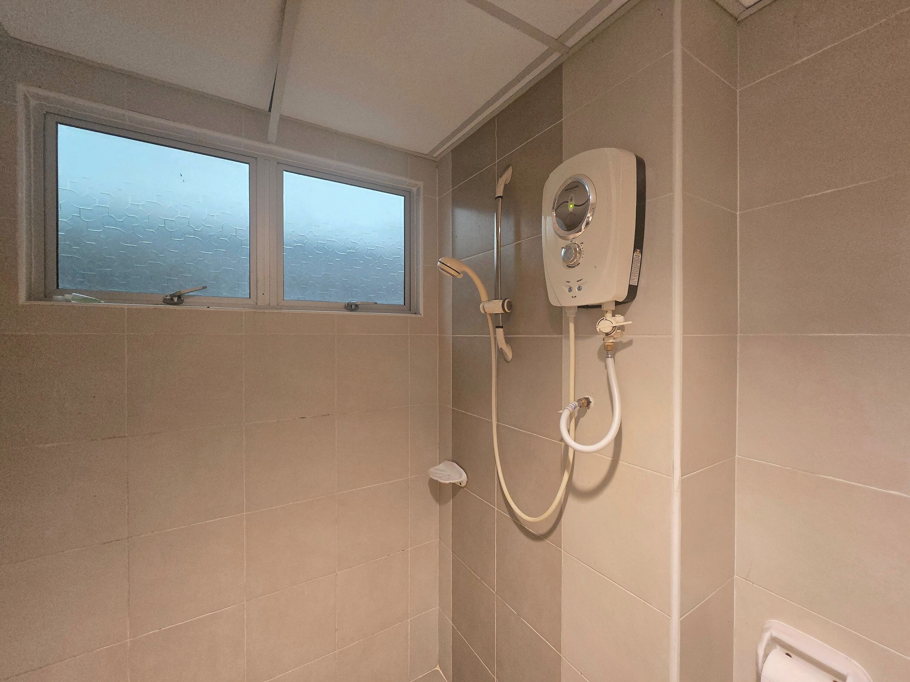 A bathroom with a shower, a window, and a wall-mounted heater.