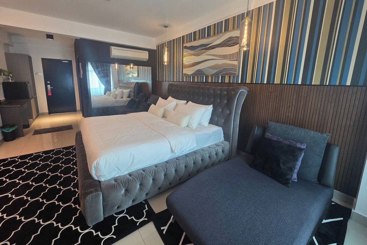 Una habitación de hotel moderna con una cama grande, un área de descanso, un escritorio y una pared con diseños a rayas.