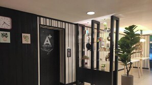 Ein Hotel-Empfangsbereich mit einer schwarz-weiß gestreiften Wand, einer Uhr und einem Empfangstresen mit Pflanze.