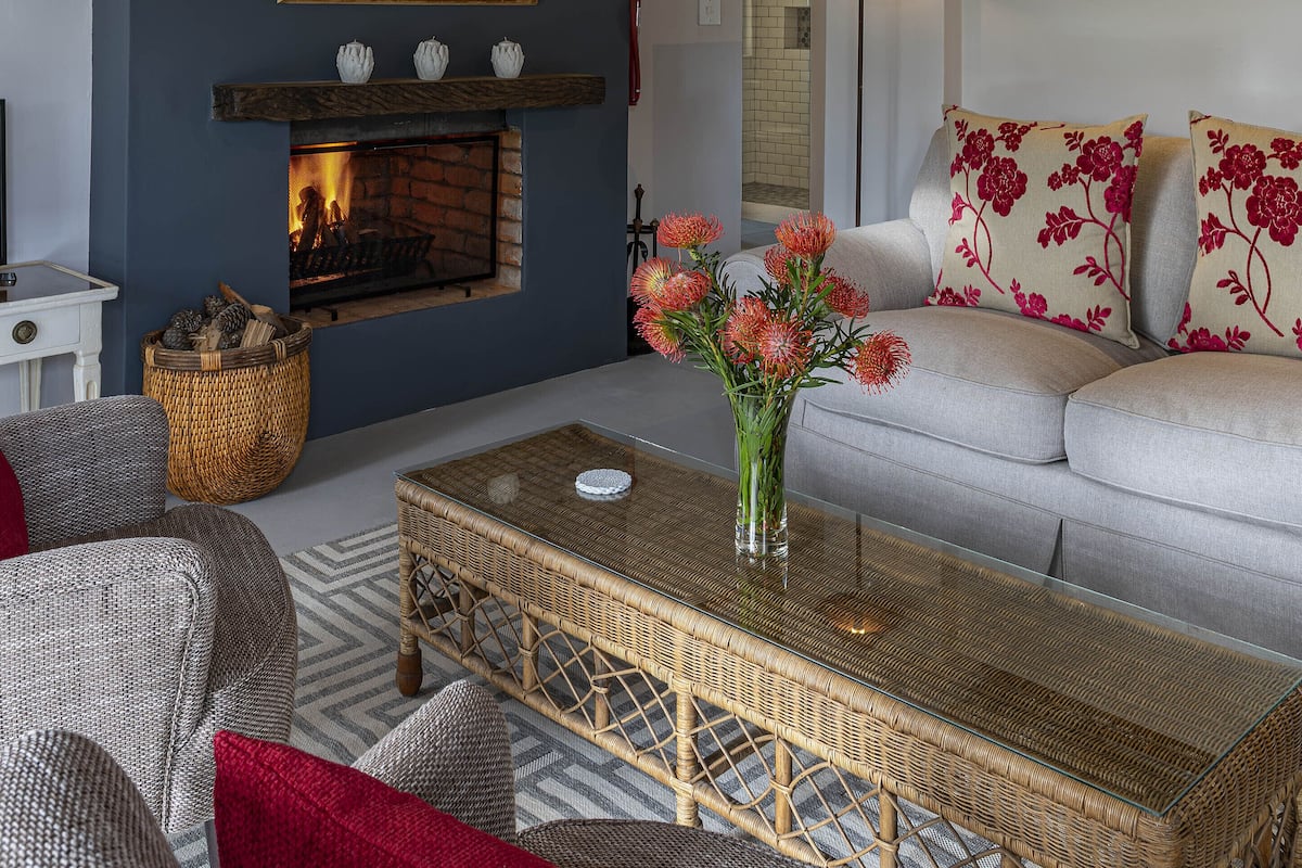 A living room with a fireplace, a sofa, a coffee table, and a wicker chair.