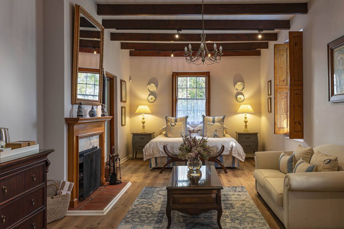 A traditional room with a fireplace, bed, and a chandelier.